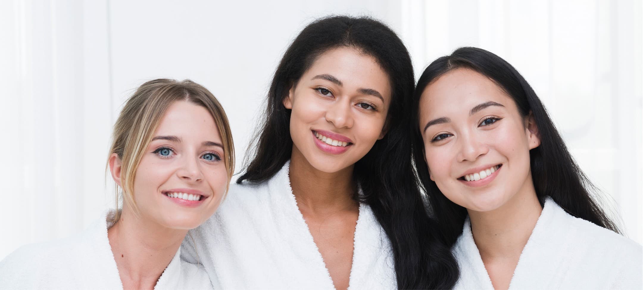 Three clients smiling in white spa robes